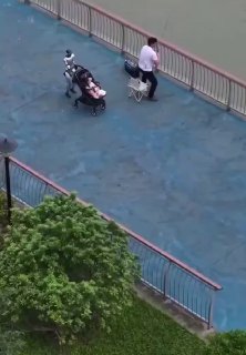 Вид сверху на набережную у воды: мужчина рыбачит у перил, рядом на дорожке детская коляска и небольшой робот-устройство.