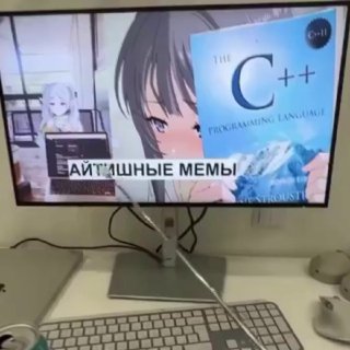 Фото рабочего стола: монитор с аниме-иллюстрацией и крупной обложкой с надписью «C++», рядом клавиатура, мышь и ноутбук.