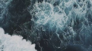 Темные бурлящие морские волны с белой пеной и вихрями воды, крупный план поверхности моря, передающий динамику и движение воды.