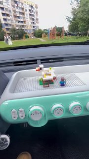 Торпедо светло-голубого микрокара с подставкой и несколькими деталями Lego, видна отделка салона и панель управления.