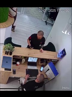 Кадр из камеры магазина: покупатель у прилавка с сумкой и сотрудник за кассой, видна часть торгового пространства.