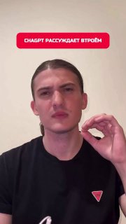 Человек в чёрной футболке на нейтральном светлом фоне, показывает жест рукой и серьёзное выражение лица, статичный кадр превью видео.