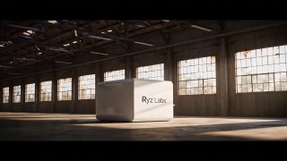 Белый куб с надписью Ryz Labs в просторном индустриальном помещении с большими окнами; жёсткий свет подчёркивает объём и фактуру пола.
