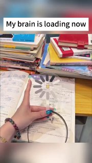 Фото учебного стола: руки держат ободок на фоне книг и тетрадей, видна надпись «My brain is loading now».