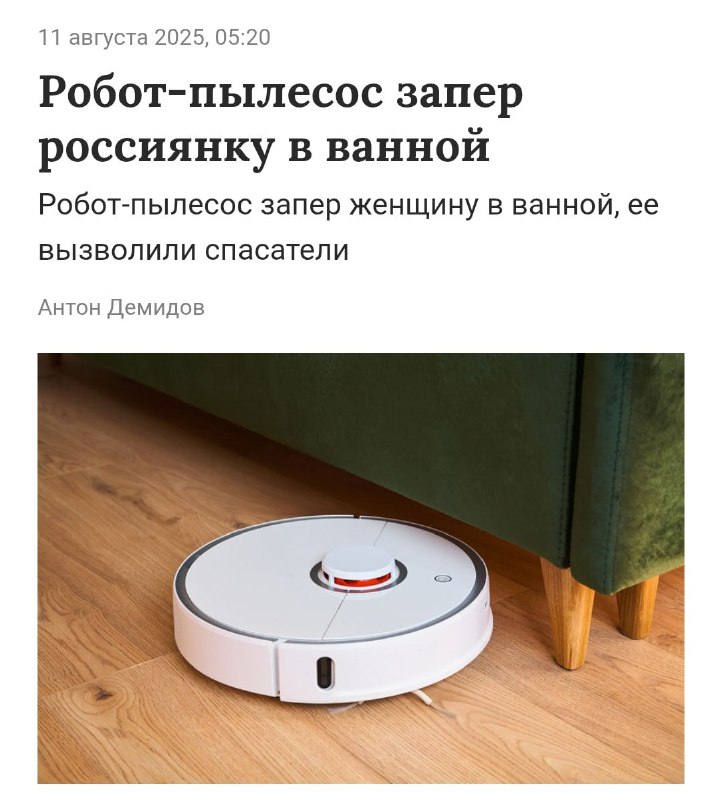 Фотография робота-пылесоса на деревянном полу у мебели, иллюстрация домашней ситуации с автоматическим прибором.