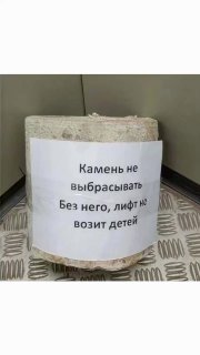 Крупный камень на полу лифта с прикреплённой бумажной табличкой на русском: «Камень не выбрасывать. Без него, лифт не возит детей»