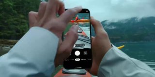 Руки, держащие смартфон Pixel, на экране виден кадр с каяками на воде и горным пейзажем; интерфейс камеры отображён.