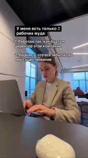Человек в офисе печатает на ноутбуке за столом, на переднем плане видна беспроводная мышь; деловой интерьер.