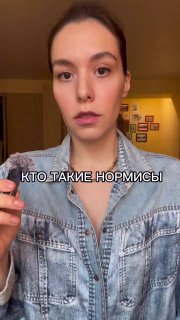 Вертикальный кадр: молодая женщина держит микрофон и говорит в камеру на фоне комнаты; поверх кадра видна подпись про «нормисов».