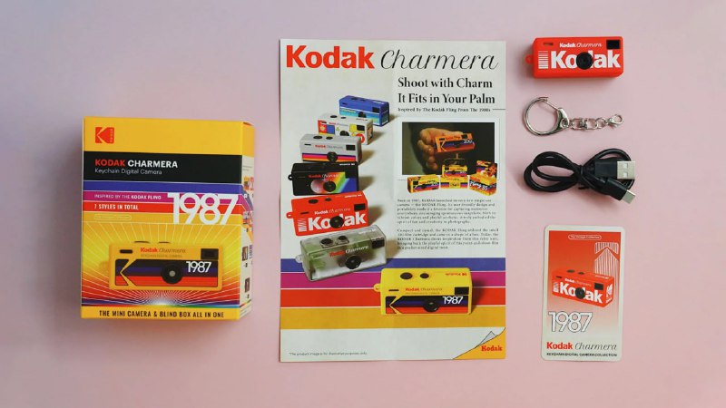 Плоская композиция: коробка Kodak Charmera, буклет, брелок-камера и кабель, разложенные для демонстрации комплектации и дизайна на нейтральном фоне.