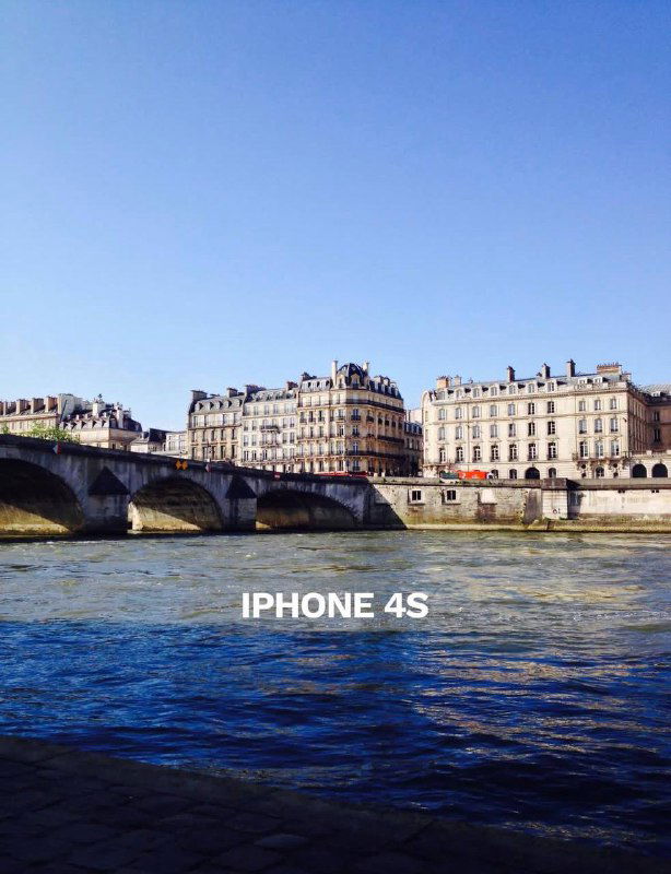 Речная набережная и старинные дома, подпись «IPHONE 4S» — кадр показывает цвет и контраст реки и зданий в съёмке старого iPhone.