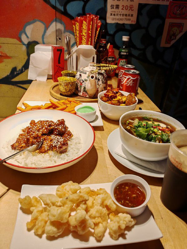 Стол с несколькими блюдами: суп Ламен, порция риса с мясом и попкорн из креветок — вид с места посетителя в ресторане Чихо.