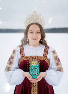 Женщина в традиционном русском костюме с украшенной короной на голове стоит на заснеженном фоне и держит матрёшку.