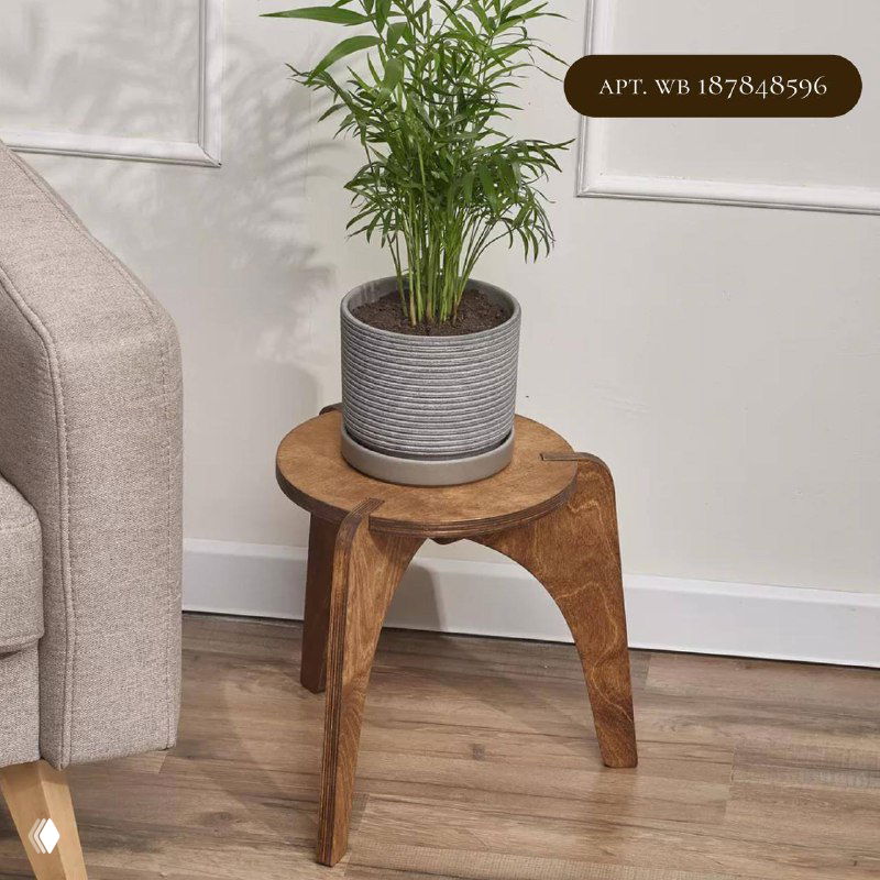 Низкая деревянная круглая подставка-стул с круглой площадкой и гладкой фактурой, на ней горшок с декоративной зеленью рядом с диваном