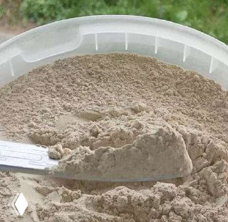 Светло-бежевый минеральный порошок в пластиковой ёмкости с лопаткой; изображён компонент удобрений — хотынецкий трепел.