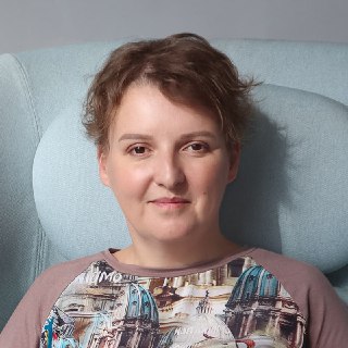 Портрет женщины в кресле с спокойным выражением лица на нейтральном фоне; фотография автора канала, семейный психолог, дружелюбный вид