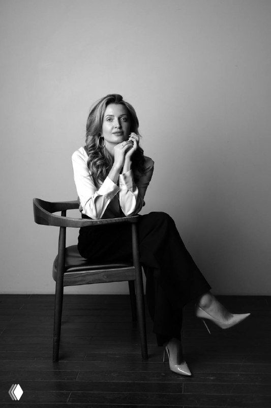 Черно‑белый портрет Юлии Макаевой, бизнес‑медиатора, сидящей в кресле в деловой одежде, задумчивый уверенный взгляд, деловая фотосессия.