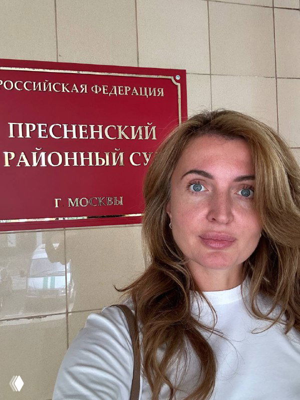 Селфи женщины на фоне таблички «Пресненский районный суд, г. Москва» — портретный кадр в коридоре суда, передаёт усталость и лёгкую иронию.