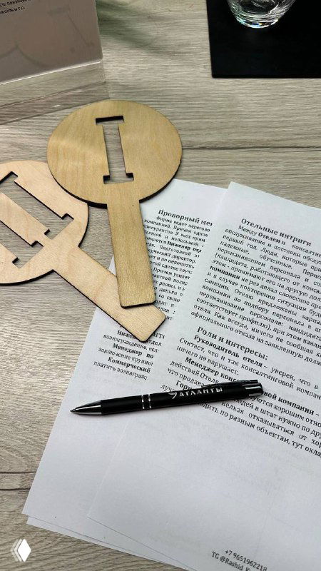 Крупный план реквизита бизнес‑игры: деревянные ключи, ручка и распечатанный кейс на столе — элементы, используемые в упражнении по переговорам.