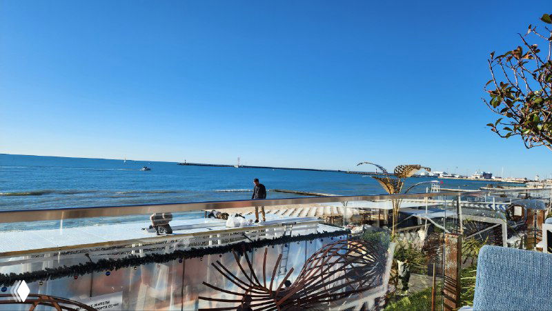 Широкий вид на море и набережную в Сочи: прогулочная зона с ограждением и столиками, спокойный морской пейзаж перед мероприятием.