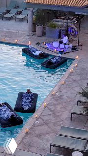 Отдыхающие лежат на надувных матрасах в бассейне днём, укрытые одеялами — демонстрация велнесс-продукта для холодного сезона в отеле.