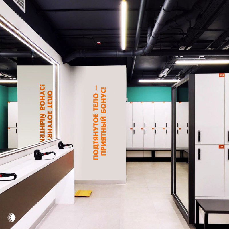 Раздевалка с шкафчиками и стойкой, где размещены вертикальные баннеры с призывными тезисами типа «Полезное тело — приятный бонус».