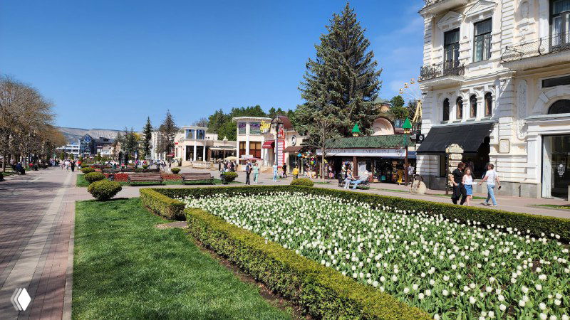 Пешеходная зона курортного центра Кисловодска с клумбами, газонами, архитектурой и прогуливающимися отдыхающими.