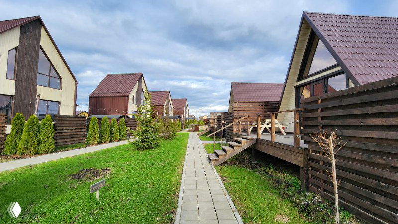 Панорамный вид на дачные коттеджи и пешеходную дорожку в Pavlov Village: уютные дома, простая дачная архитектура и открытое пространство для прогулок.