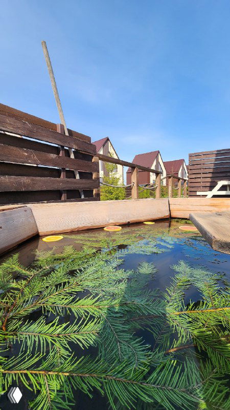 Крупный план чана для спа с деревянным обрамлением в Pavlov Village, вода с элементами декора и природными веточками, атмосфера дачного релакса.