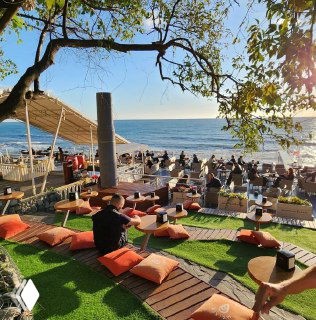 Набережная и летняя прибрежная лаунж-зона в Сочи с сиденьями и столиками у моря — вид, иллюстрирующий атмосферу отдыха во время хаба.