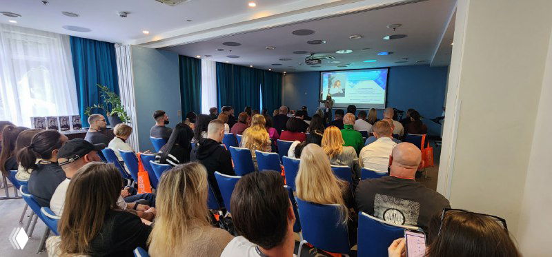 Зал конференции, участники в креслах смотрят на сцену; кадр показывает масштабы и плотность аудитории на событии.