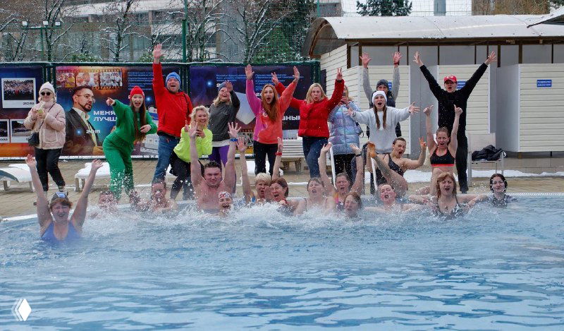 Группа участников Zumba Camp прыгает в открытом бассейне на фото; организатор подпрыгивает и улыбается рядом.