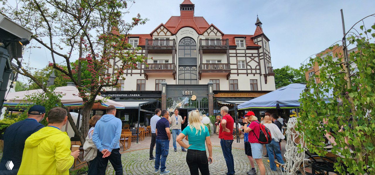 Участники фитнес-кэмпа у фасада отеля в Калининградской области: прогулка группой, обсуждение маршрута и впечатлений.