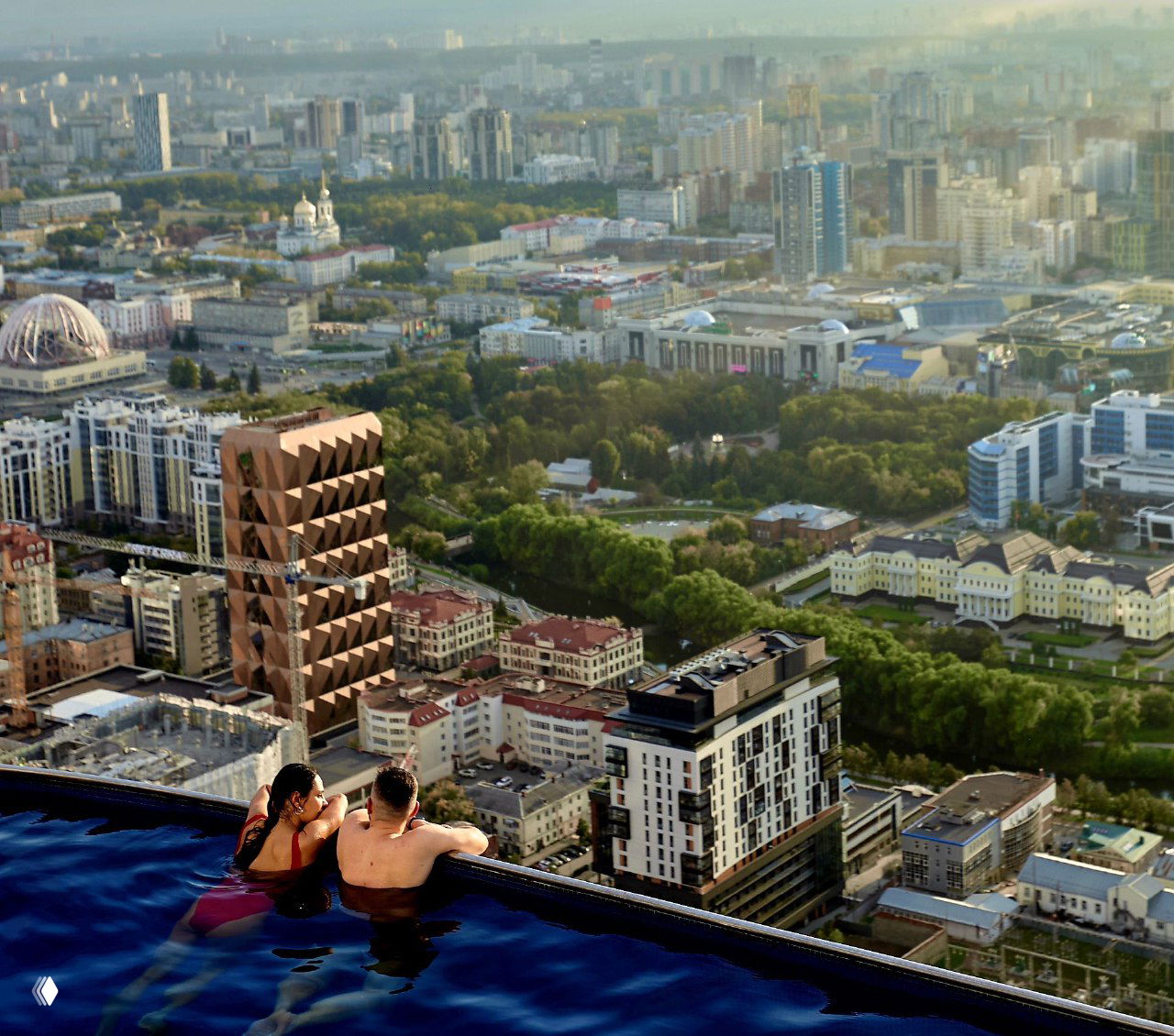 Двое людей в крыше‑бассейне на небоскрёбе с панорамой Екатеринбурга внизу — кадр вечерней тусовки третьего дня конференции.