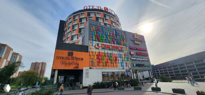 Фасад здания с крупными вывесками и логотипом отеля Idera, городской квартал у станции Нижегородская, прохожие у входа.