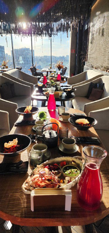 Сервированный стол с уральскими блюдами в видовом ресторане Bright Fit; вид на Екатеринбург, атмосфера деловой программы.