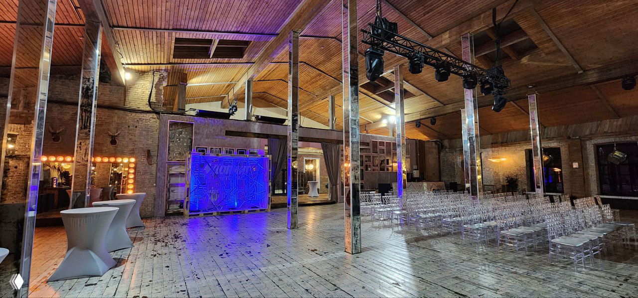 Интерьер локации: деревянный пол, зеркальные колонны и оформленная зона — пространство для тусовки и нетворкинга до и после ивента.