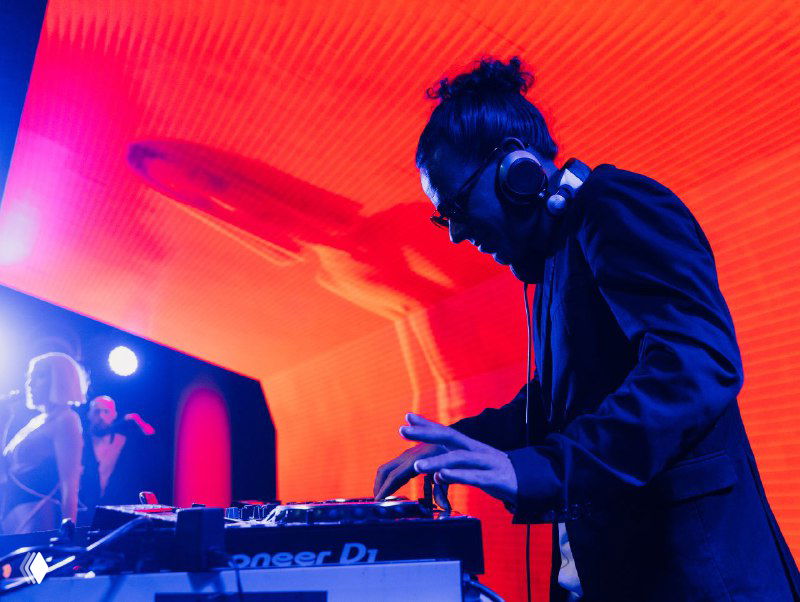 Ди-джей на сцене Bright Conf в наушниках под красной LED-подсветкой, пульт и музыка создают атмосферу ивента и вечерней программы.