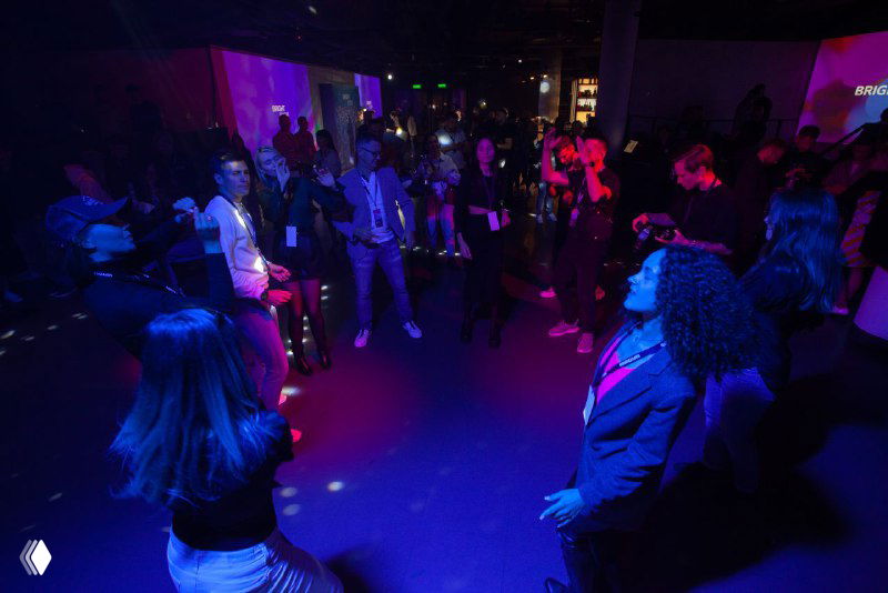 Участники на танцполе Bright Conf во время вечерней программы; цветные прожекторы, свободная атмосфера и люди в движении.