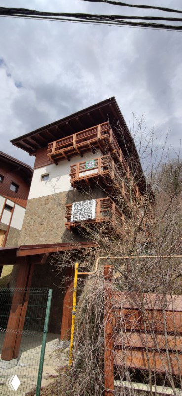 Фрагмент фасада отеля в Сочи с выступающими деревянными балконами, ограждением и пасмурным небом — возможные места для размещения QR-кодов.