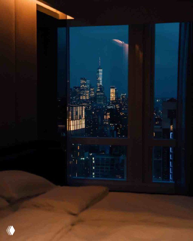 Вид из номера ночью на городской пейзаж с огнями небоскрёбов — атмосферный снимок, усиливающий ощущение урбанистического отдыха.
