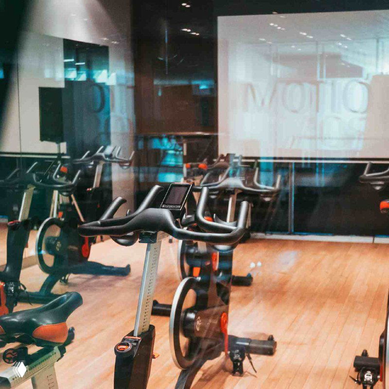 Зал групповых программ и велотренажёры в First & Only: аккуратная расстановка оборудования и зеркальные поверхности в уютной обстановке.