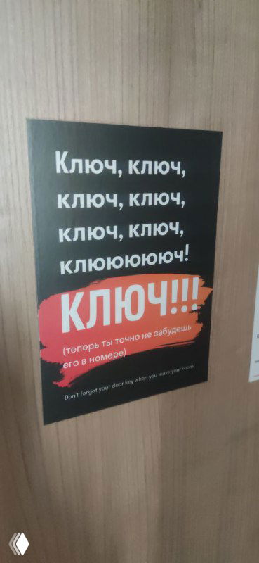 Плакат в коридоре отеля с повторяющимся текстом «Ключ, ключ, ключ... КЛЮЧ!!!», яркий дизайнерский элемент, привлекающий внимание гостей.