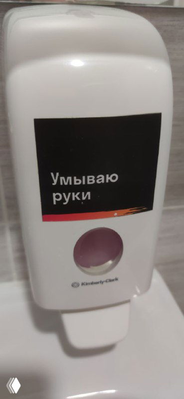 Дозатор для жидкого мыла в ванной с этикеткой «Умываю руки», чёрная табличка с белой надписью и фирменной полосой — элемент сервиса и коммуникации бренда.
