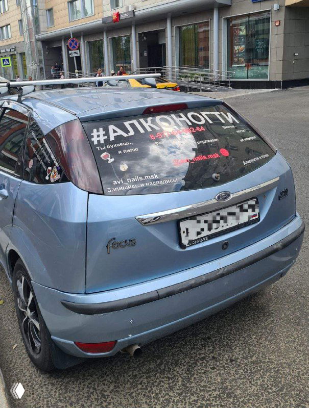 Фотография рекламного сообщения на заднем стекле автомобиля: бренд «АЛКОНОГТИ», слоганы про вино и маникюр, пример смешения услуг в wellness-индустрии.