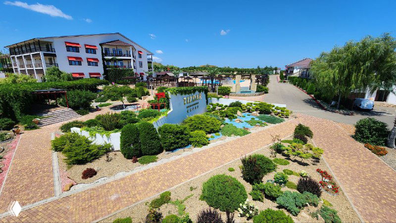 Панорамный вид благоустроенной территории курорта Тиздар в Кубанском крае: дорожки, клумбы, корпуса и зелёные насаждения.