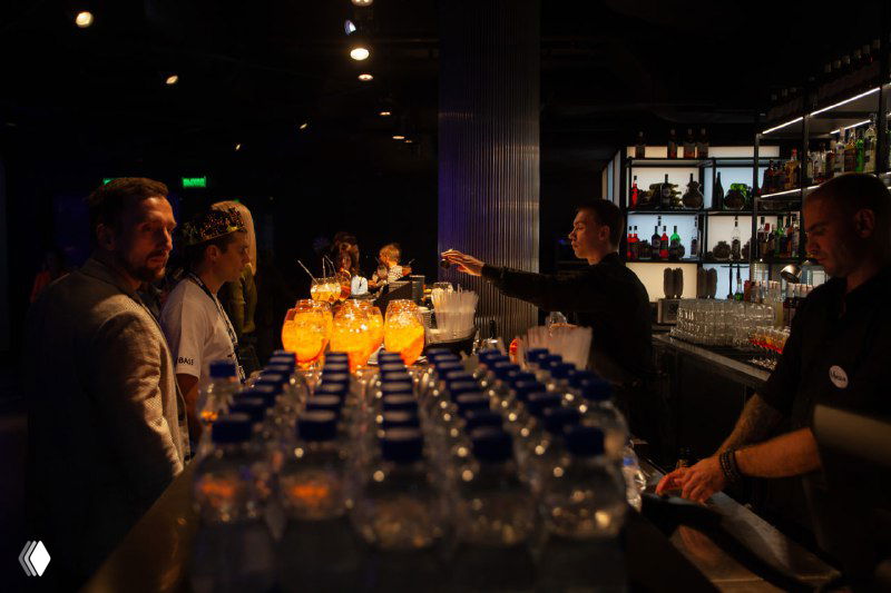 Барная стойка и сервировка с бутылками воды и бокалами апероля: подготовка фуршета и обслуживание участников мероприятия.