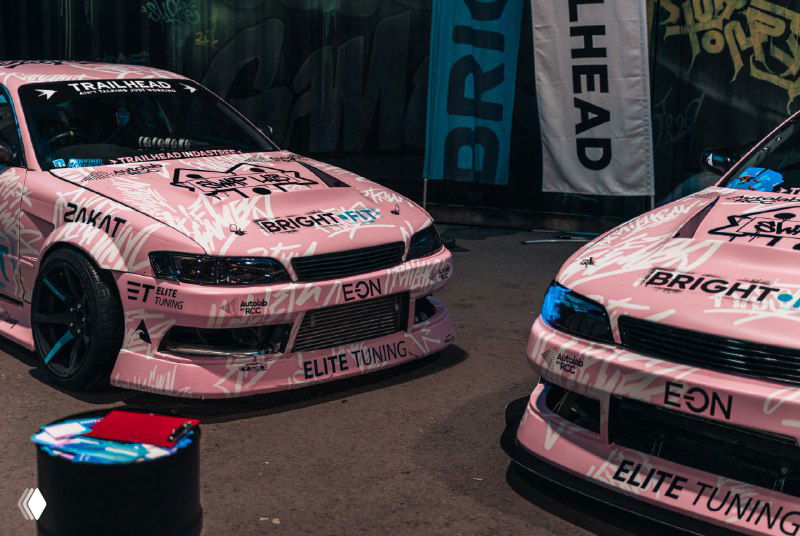 Два розовых брендированных автомобиля в оформлении ивента — элементы брендирования и визуального оформления площадки.