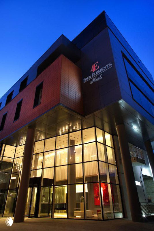 Ночной фасад современного городского отеля в Екатеринбурге с подсвеченным входом и витринами — иллюстрация партнерства отельеров с отраслевым ивентом