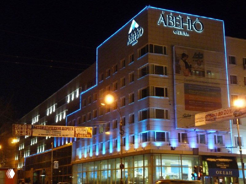 Ночное фото фасада крупного гостиничного комплекса с неоновой подсветкой и вывесками, показывающее масштабы городской гостиничной инфраструктуры